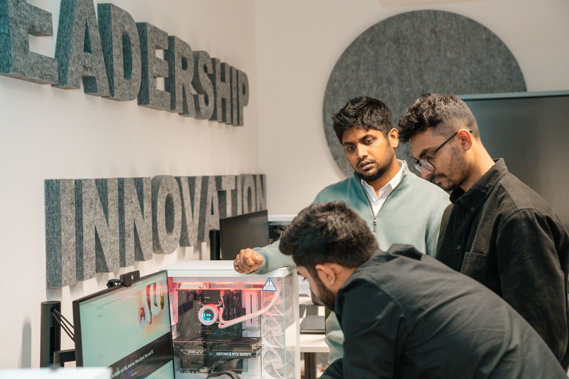 Three men collaborate in an office, focusing on tech innovation. Leadership and team dynamics emphasized.