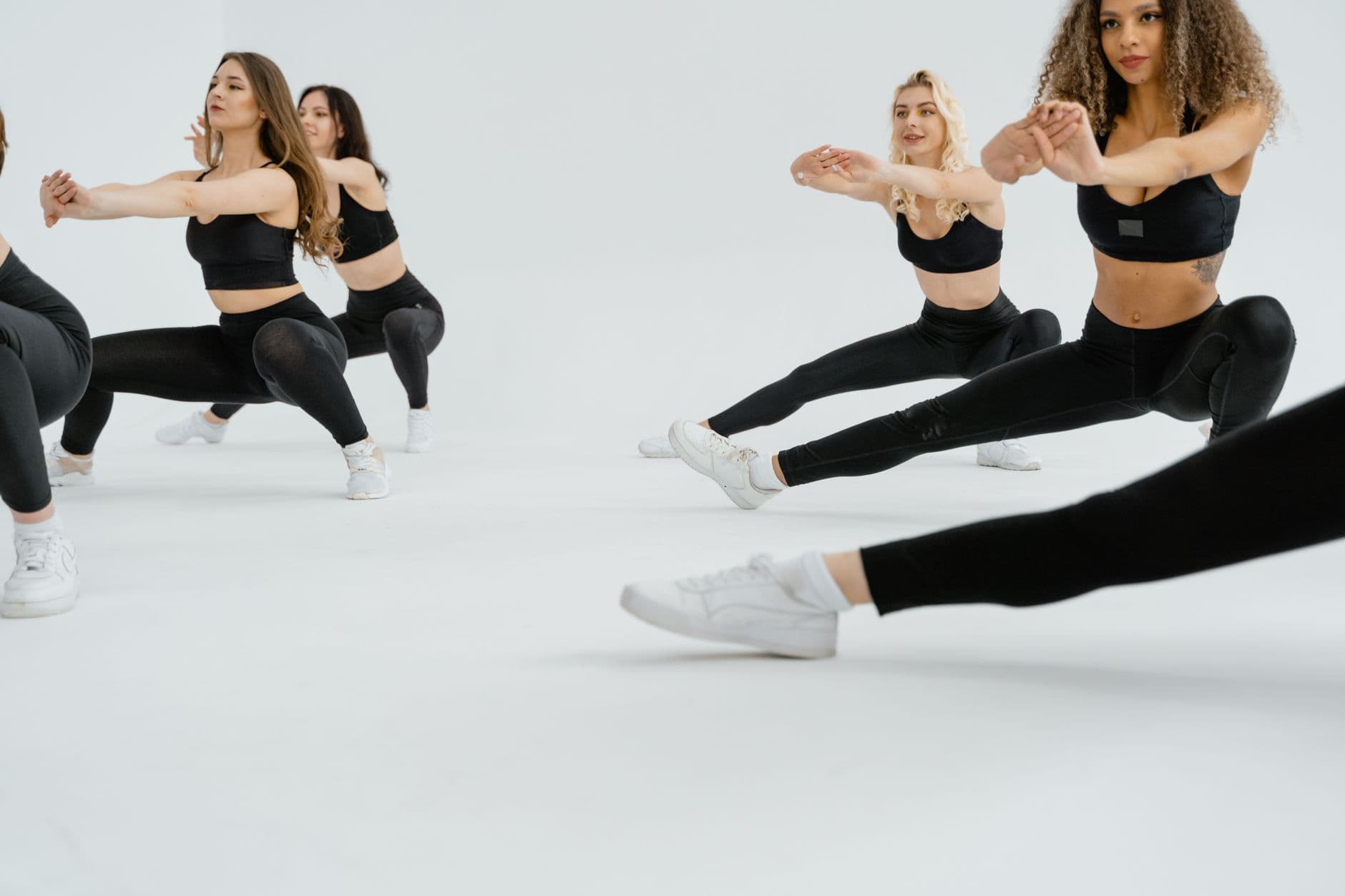 Dynamic image of women exercising in stylish activewear indoors, promoting a healthy lifestyle.