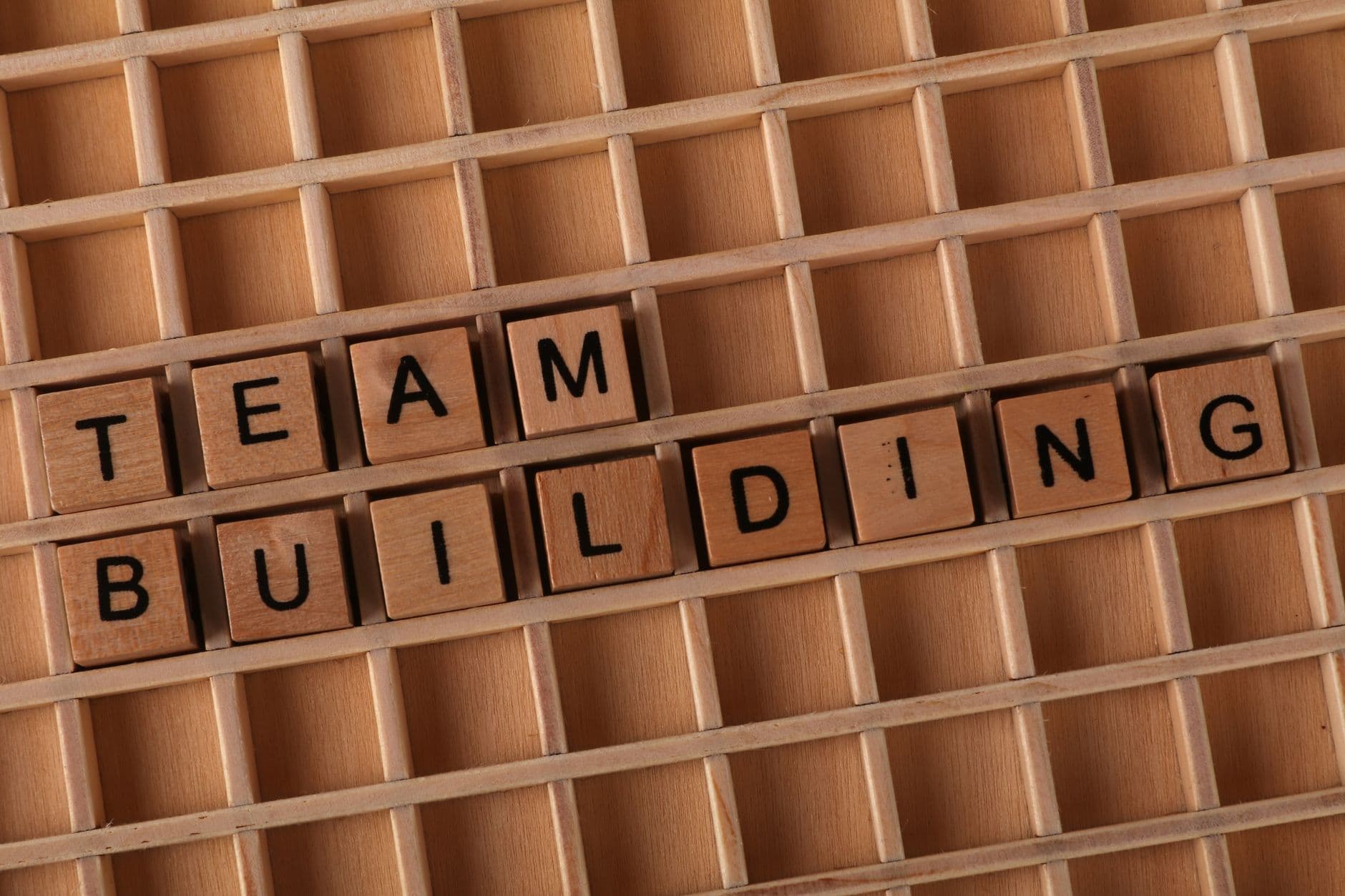 Scrabble letters spelling 'TEAM BUILDING' on a wooden board symbolize teamwork and collaboration.